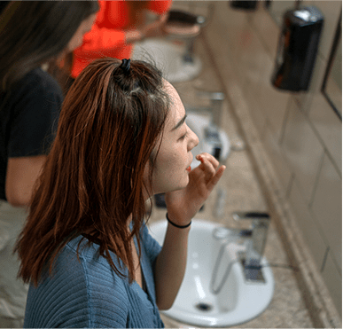 Young lady getting ready in front of a mirror